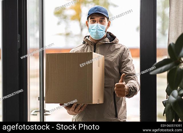 delivery man in mask with box showing thumbs up