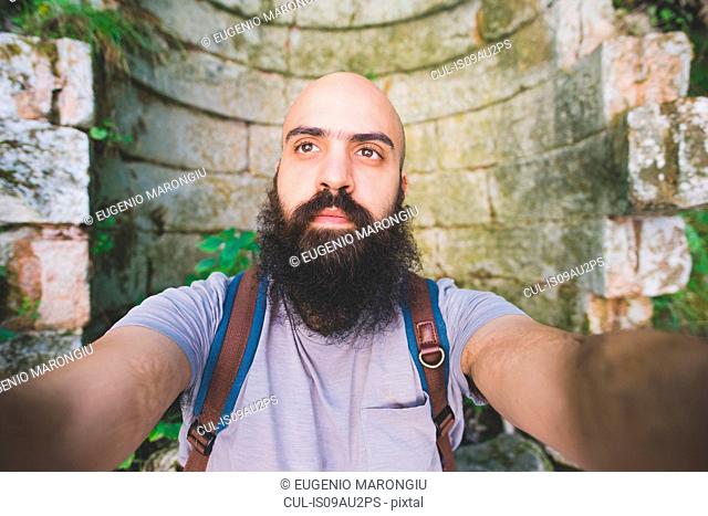 Bearded man posing against old brick wall, Garda, Italy