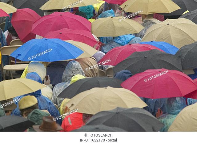 Guests hold umbrellas in the rain as they attend the official opening ceremony of the Clinton Presidential Library