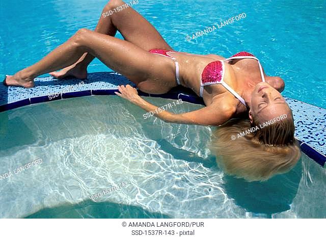 Young woman lying on a wall in a swimming pool
