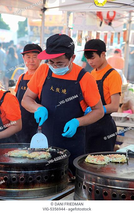 CANADA, MARKHAM, 24.07.2015, A food vendor preparing Okonomiyaki (Japanese pancakes containing a variety of ingredients) during an all-night Chinese market held...