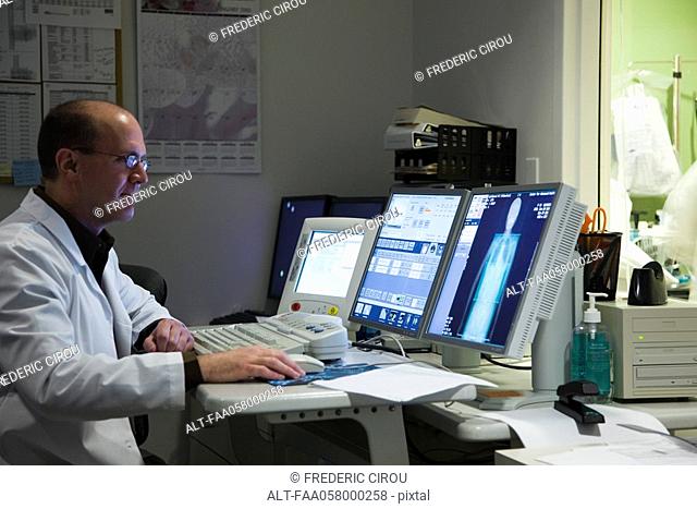 Male doctor evaluating medical exam result on computer monitor