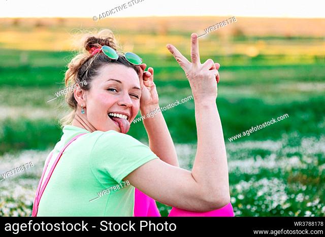 young woman, carefree, sticking out tongue, victory sign