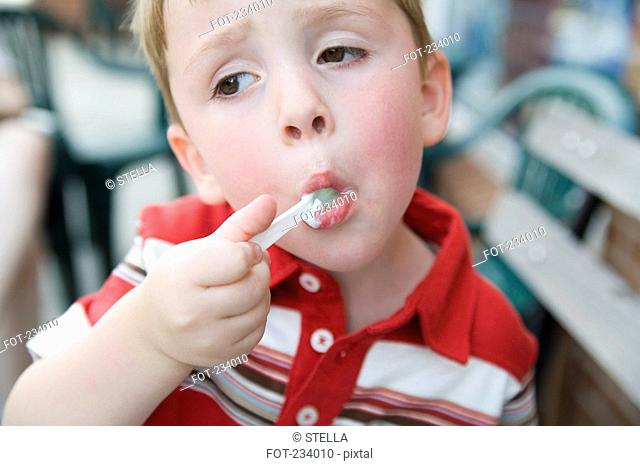 Young boy eating ice cream with spoon