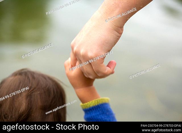 01 July 2023, Berlin: A mother holds her child by the hand. As part of the austerity measures in the federal budget, there could be changes to parental...