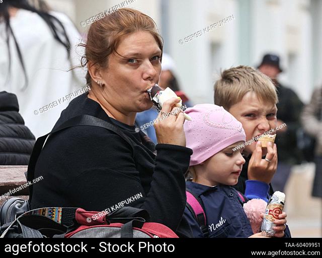 RUSSIA, MOSCOW - JULY 12, 2023: A woman and children eat ice cream in central Moscow. With the temperature reaching only +17°C (62