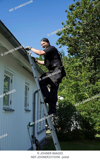 Chimney sweep climbing on roof