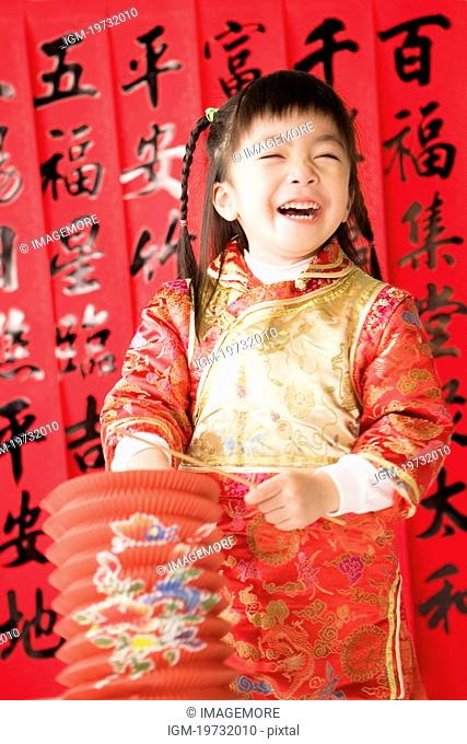 Girl in Chinese traditional clothes with lantern standing and laughing