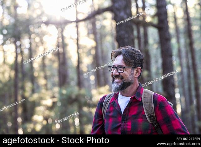 Close up portrait of confident bearded man in a outdoor park. Profile young handsome smiling bearded man Young adult hipster hiking forest - happy people...