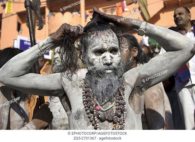Naga sadhu covered in ash tying his hair. Kumbh Mela 2016. Ujjain, Madhya Pradesh, India