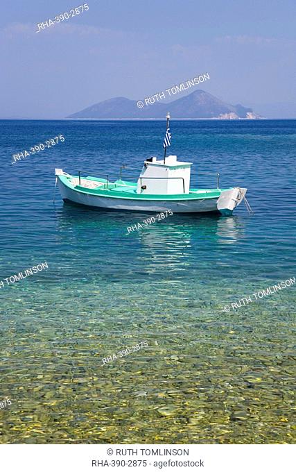 Small boat anchored offshore, the island of Atokos visible on horizon, Kioni, Ithaca (Ithaki), Ionian Islands, Greece