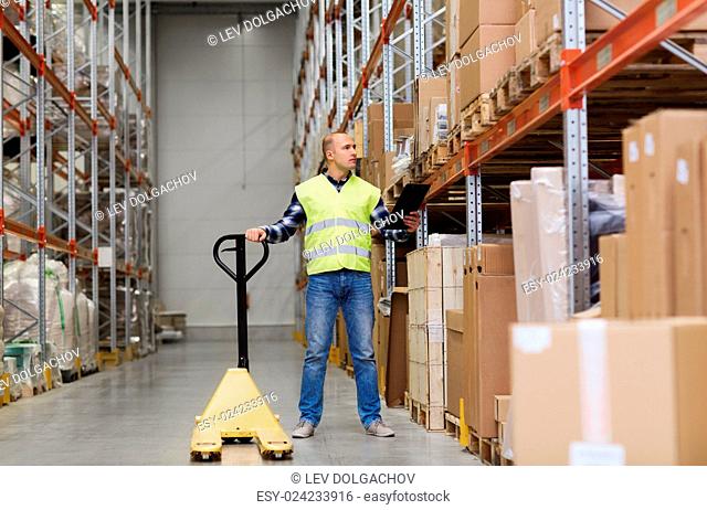 wholesale, logistic, loading, shipment and people concept - man with loader and clipboard at warehouse