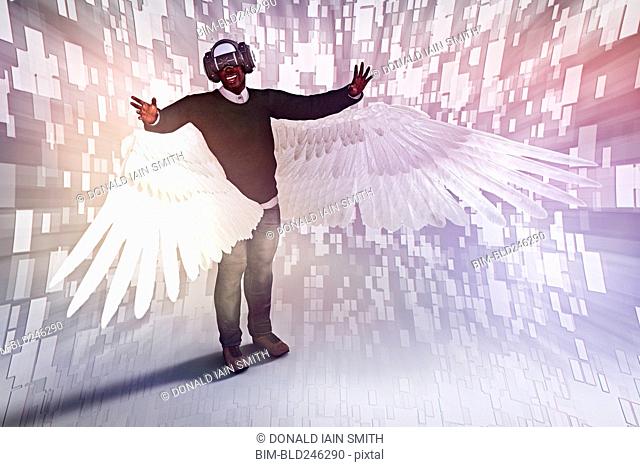 Man with angel wings wearing virtual reality helmet