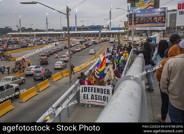 22 May 2022, Mexico, Tijuana: ""Stand for asylum, "" reads the placard migrants hold up at a rally at the San Ysidro border crossing against the so-called...