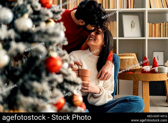 Young man kissing girlfriend on forehead at home