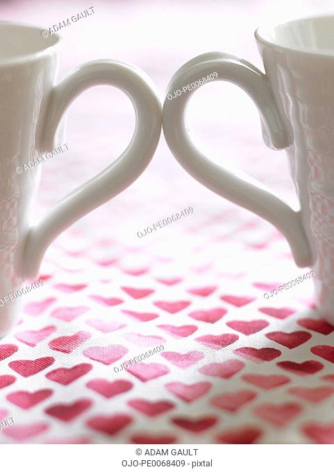 Close up of two coffee cups on table cloth decorated with hearts