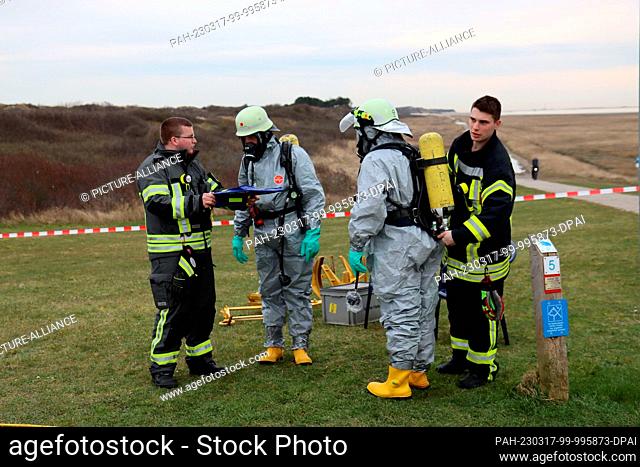 17 March 2023, Lower Saxony, Wangerooge: Emergency personnel in protective suits and firefighters prepare during a major exercise of the emergency response team...