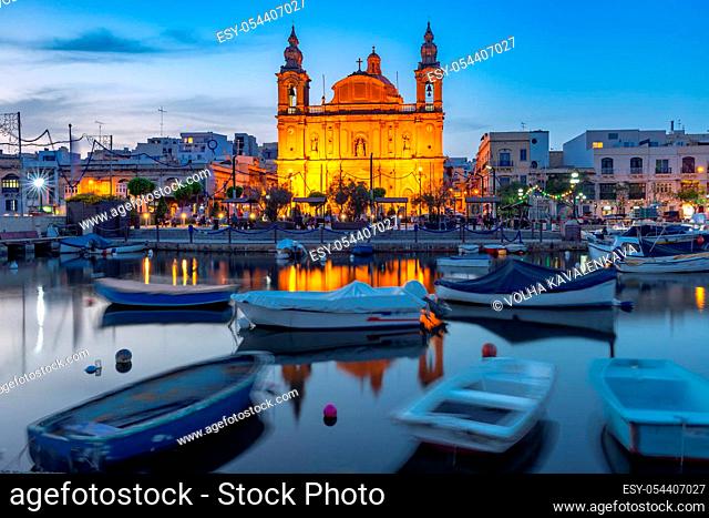 Valletta harbour with yachts and fishing boats, Msida Parish Church of Saint Joseph at sunset, Malta
