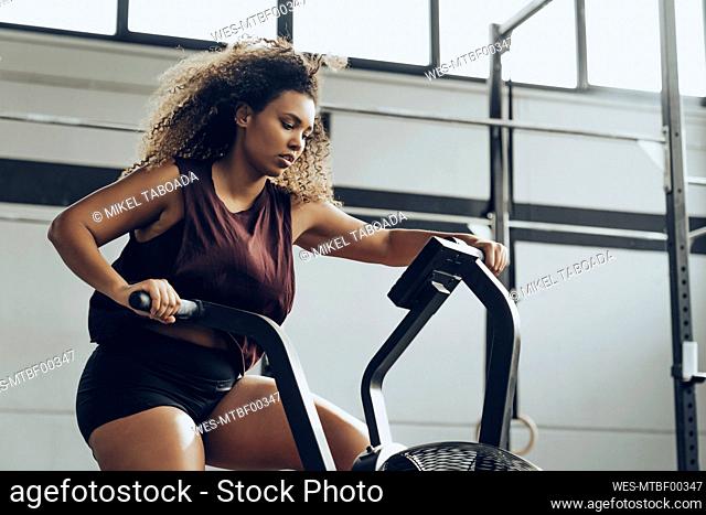 Young woman doing air bike workout in gym