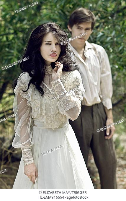 A young woman walking away from a young man dressed in period costume