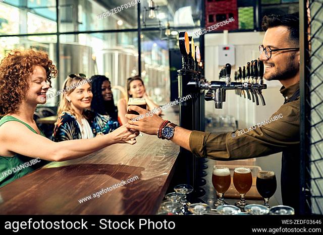 Barkeeper handing over glass of beer to woman in a pub