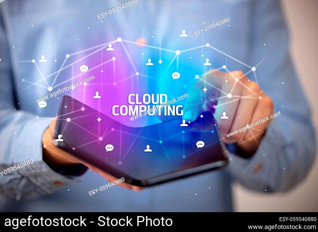 Businessman holding a foldable smartphone with CLOUD COMPUTING inscription, new technology concept