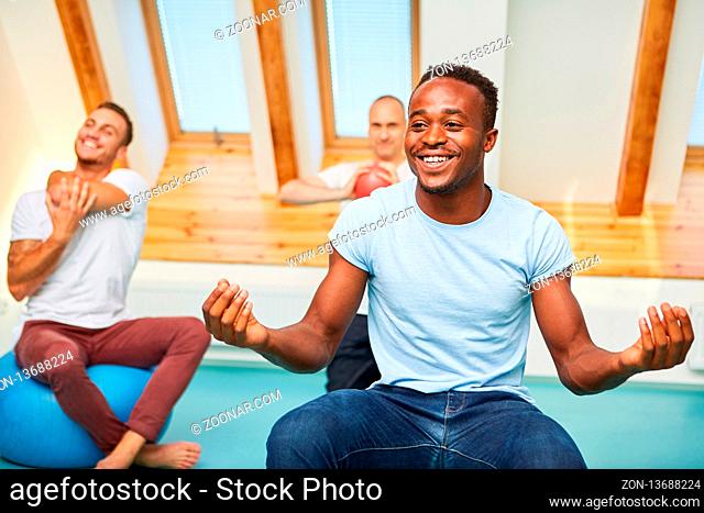 Afrikanischer Mann in einem Wellness Kurs macht eine Yoga Übung für die innere Ruhe