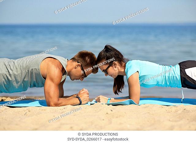 couple doing plank exercise on summer beach