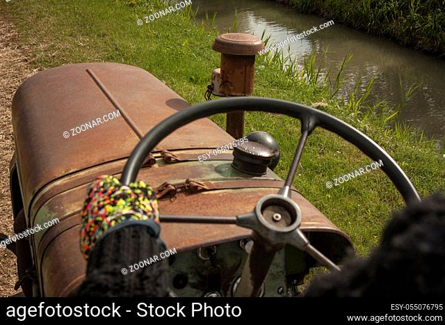 First-person image in driving a vintage tractor to cultivate farm fields and campaign