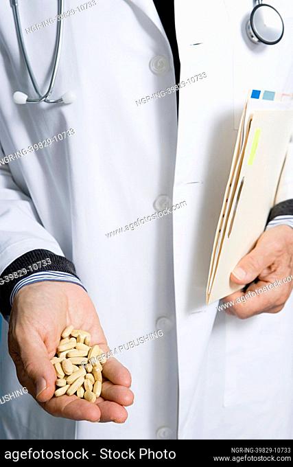Doctor holding pills and a document