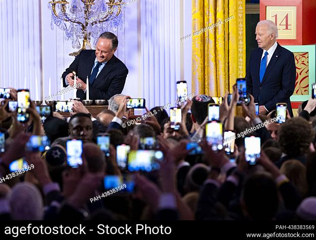 United States President Joe Biden looks on as second gentleman Douglas Emhoff lights the menorah during a Hanukkah Holiday Reception in the East Room of the...