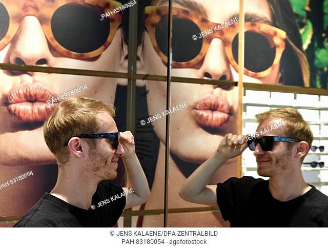 Max Frank, employee at 'Ace and Tate', tries on glasses in the flagship store of the Dutch glasses brand 'Ace and Tate' in Neue Schonhauser Strasse in Berlin