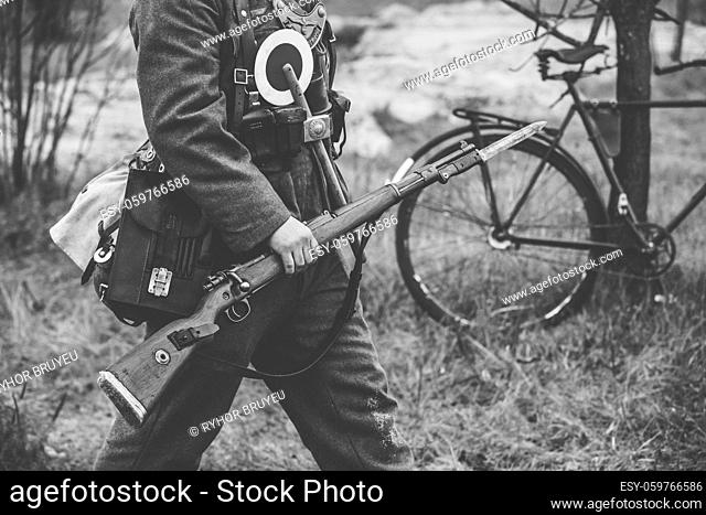 Re-enactor Dressed As World War II German Soldier Feldgendarm Holding Rifle. Photo In Black And White Colors. Soldier Holding Weapon