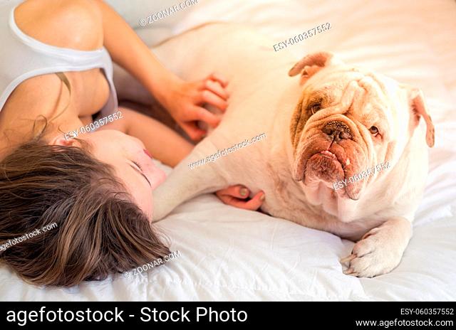 Beautiful woman sleeping in bed with english bulldog puppy