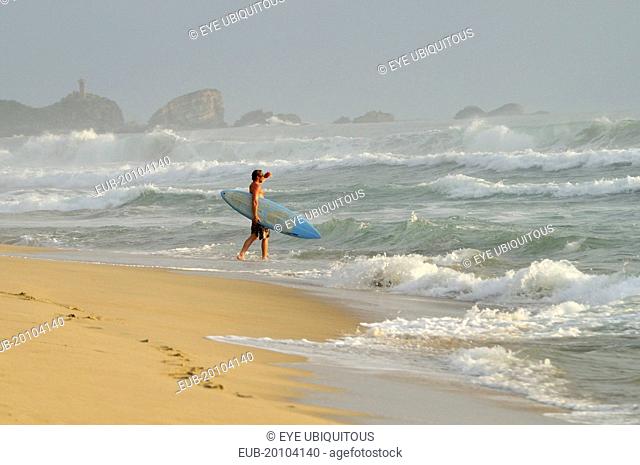 Surfer walking into surf carrying board