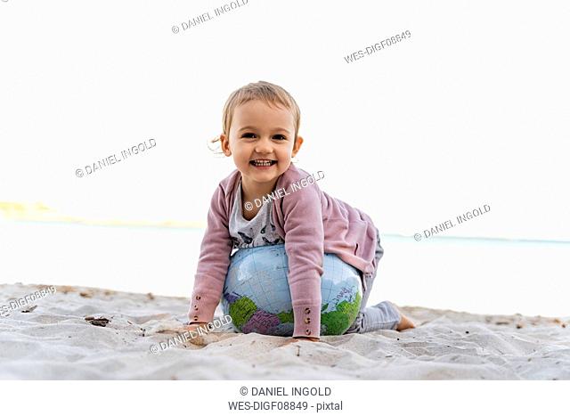 Portrait of happy little girl playing with Earth beach ball