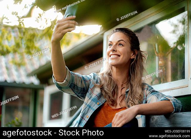 Happy woman taking selfie through mobile phone in backyard