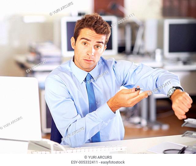 Young businessman indicating at his wristwatch with a questioning expression