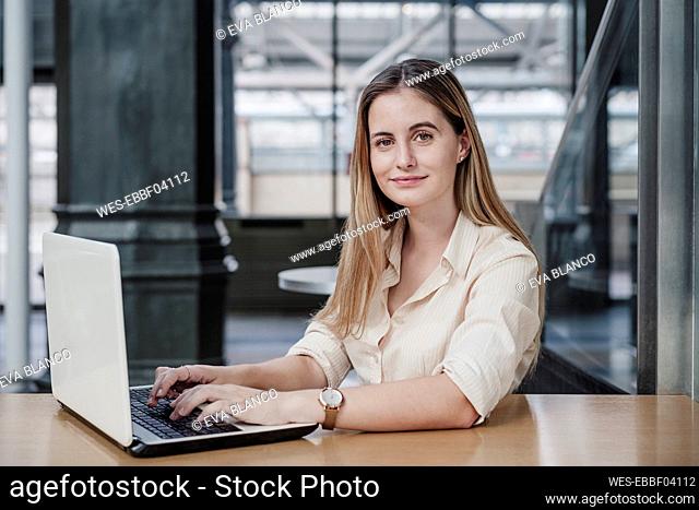 Beautiful young businesswoman sitting with laptop in cafe