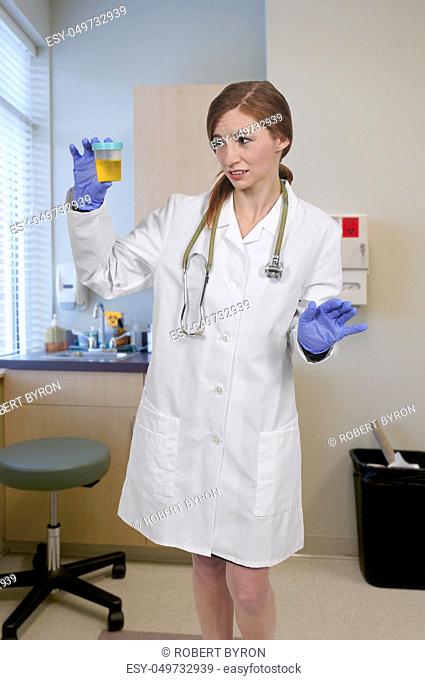 Beautiful young woman doctor holding a urine sample