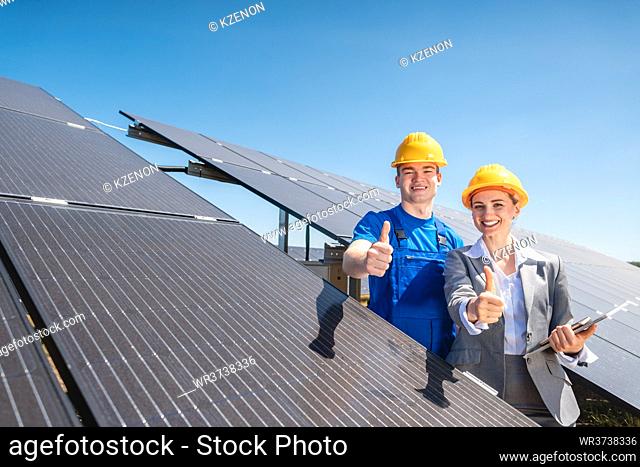 Worker and investor in solar power plant pointing at the sun