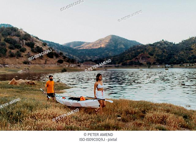 Couple carrying kayak by lake, Kaweah, California, United States