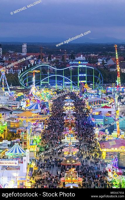 Germany, Bavaria, Munich, Drone view of crowds of people celebrating Oktoberfest in vast amusement park at dusk