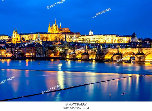 St. Vitus Cathedral and Prague Castle lit up during the evening blue hour reflecting in the Vltava River, UNESCO World Heritage Site, Prague, Czech Republic