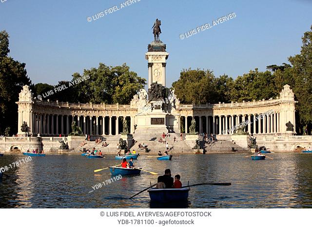 Tourists enjoying the boats in Retiro Park Pond with its monument and statue of Alfonso XII, Madrid, Spain, Europe