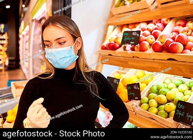 Kundin mit Mundschutz wegen Covid-19 Pandemie beim Einkaufen im Supermarkt