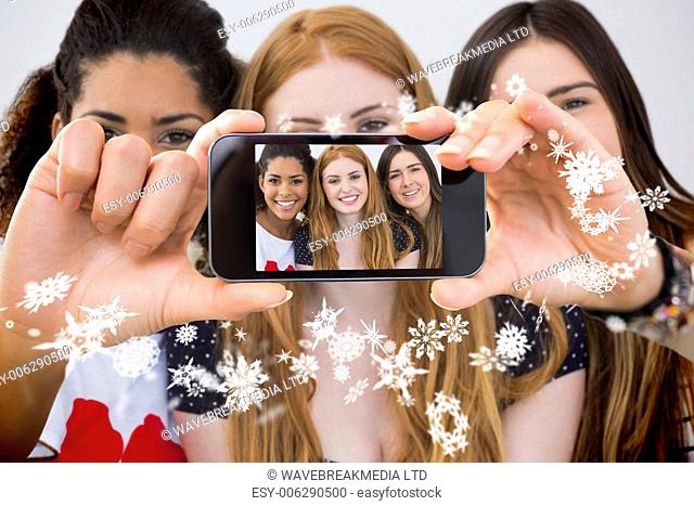 Hand holding smartphone showing close up portrait of cheerful female friends