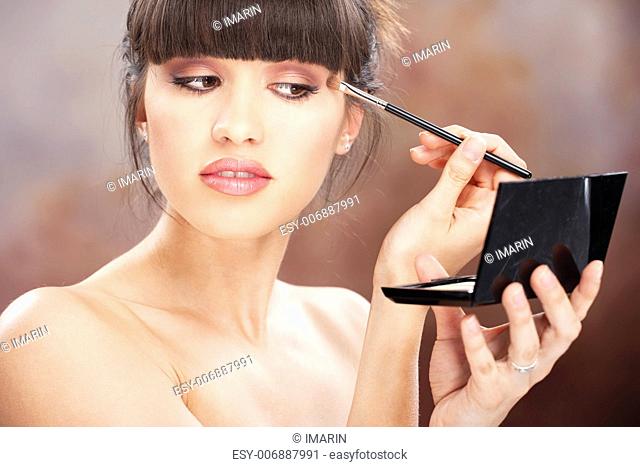 pretty woman applying make up with brush