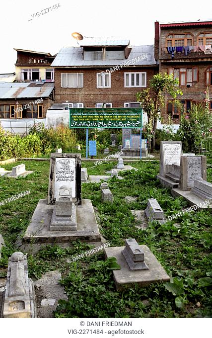 INDIA, SRINAGAR, 23.06.2010, A banner for Muslim martyrs along with graves of many martyrs killed in service to Islam in a Muslim cemetery in the Old City in...