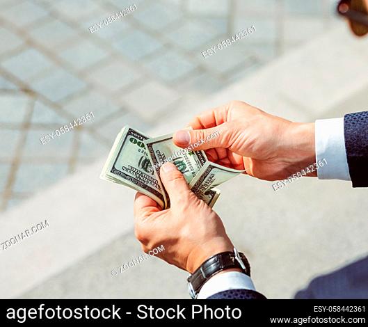 Men's hands hold dollars. Successful businessman considers salary.Male arms with watch, close up shot. High quality photo